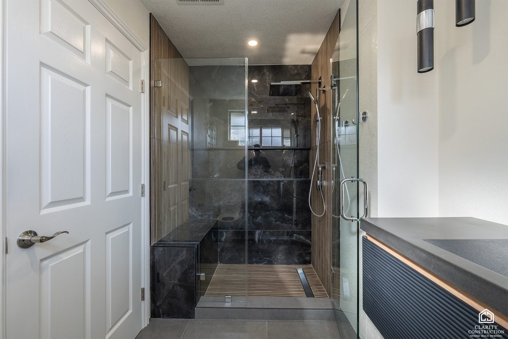 Second bathroom seen from the hall with its dark tile shower