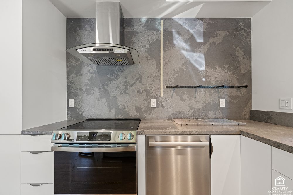 Gas range under a stainless hood with a marbled backsplash