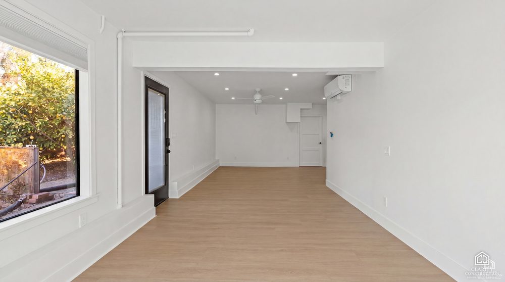 Open living area of the converted garage with new flooring and a glass door