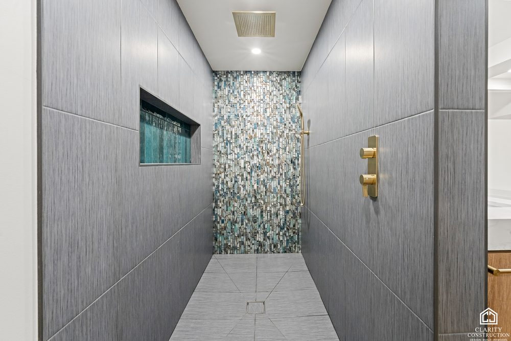 Walk-in shower with a green mosaic accent wall and gray tile