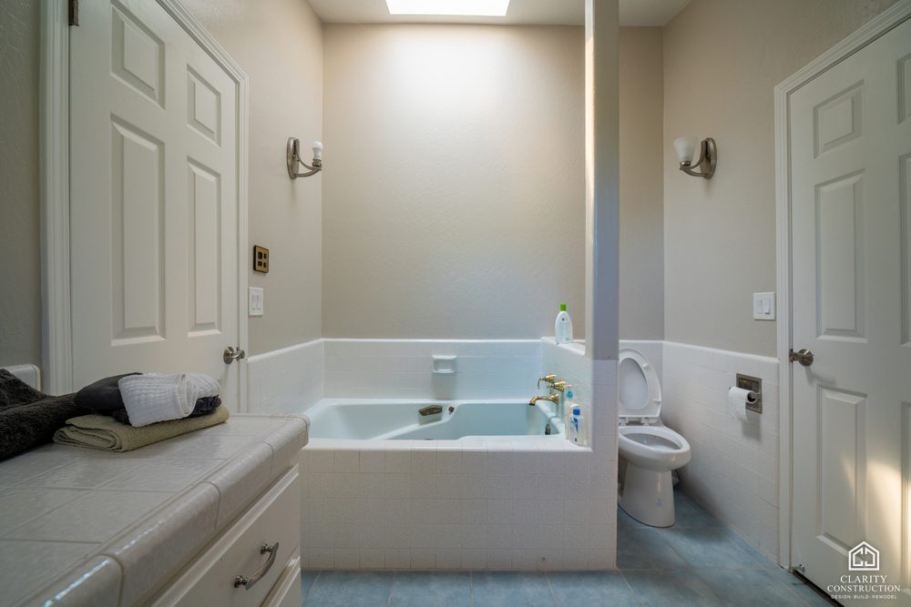 The original primary bathroom with a beige tile tub and a stall shower