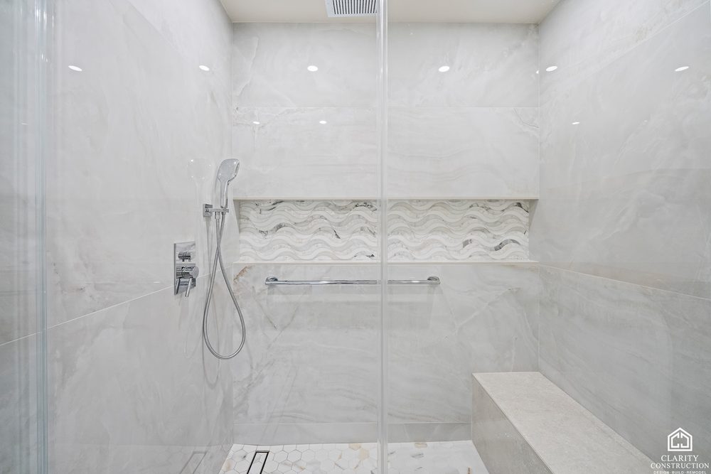 Large-format tile shower with a bench and a wave-patterned stone niche