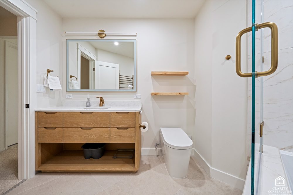 Floating oak vanity with a backlit mirror and open wood shelves