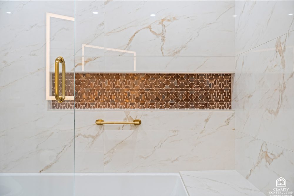 Copper penny-tile niche and brass grab bar set into marble-look tile