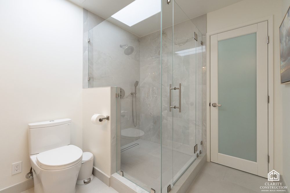 Walk-in shower behind glass beside the toilet, with a frosted glass door