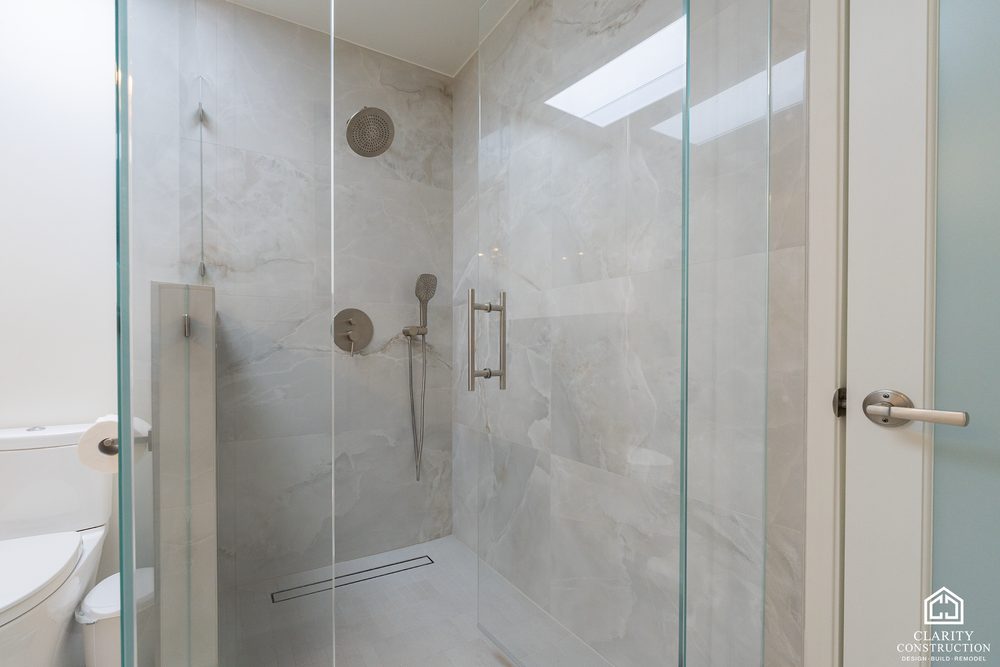 Large-format tile walk-in shower with a hand shower and a skylight