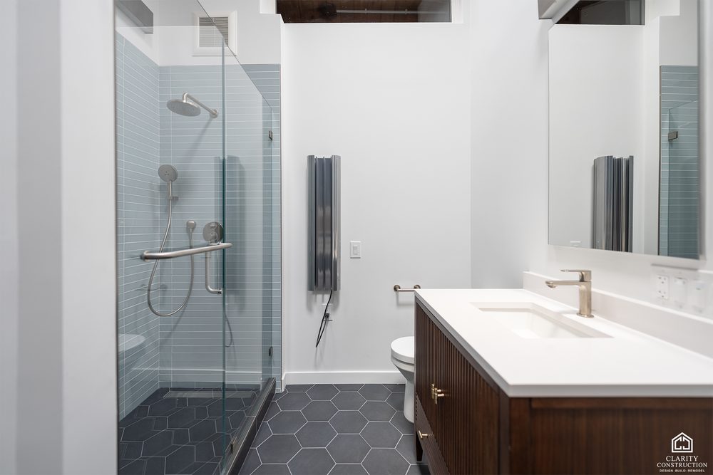 Bathroom with a walnut vanity, a white counter and a glass-tile walk-in shower