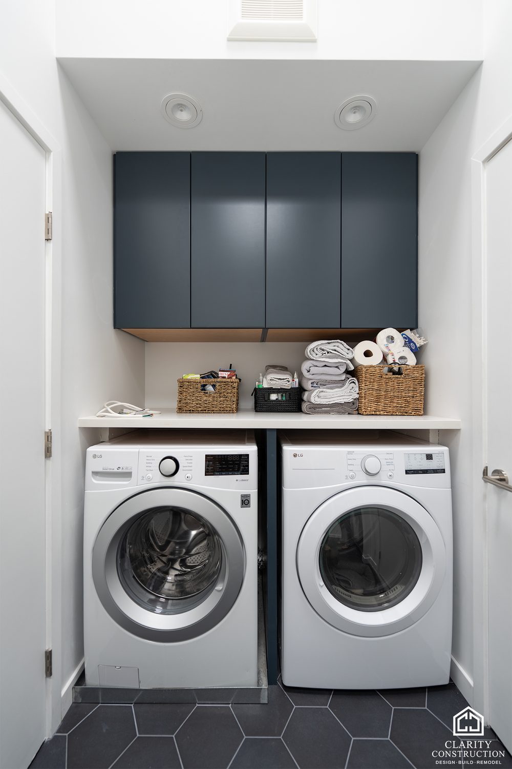 Laundry closet with navy cabinets over a washer and dryer