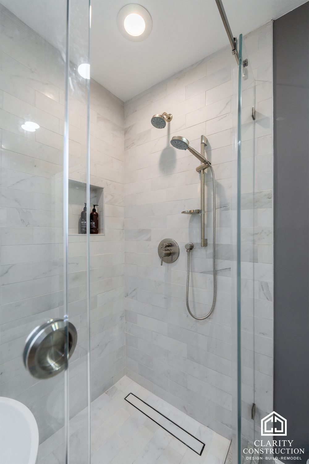Shower fixtures and a niche in the tiled wet room behind glass
