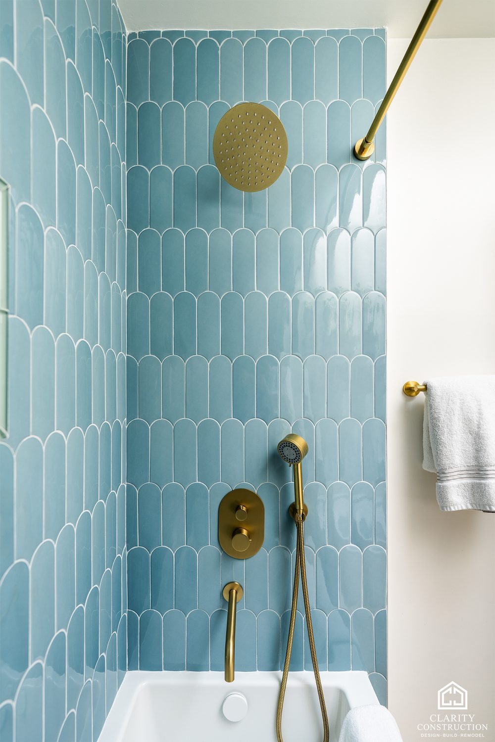 Brass rain head and blue picket tile in the tub surround