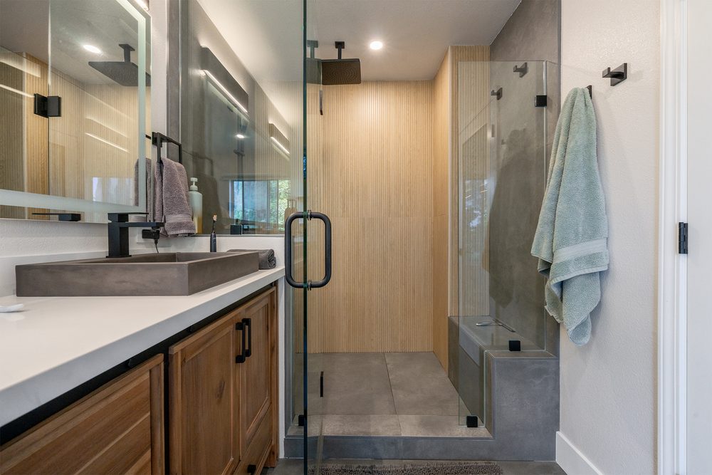 Walk-in shower with wood-look and charcoal tile, a bench and a hand shower