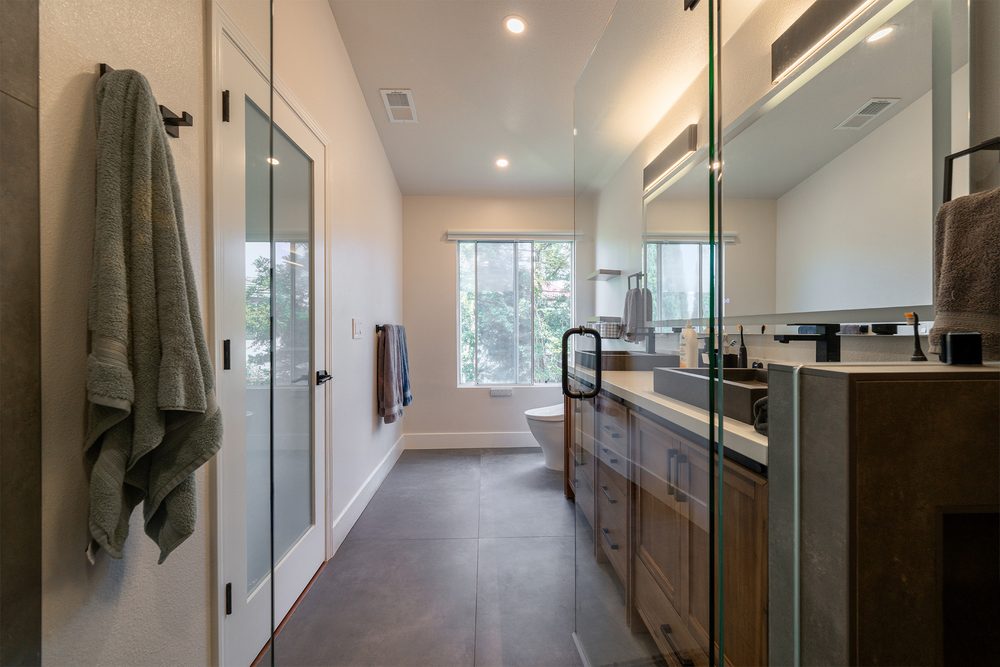 Long view of the primary bathroom with the vanity and the glass shower