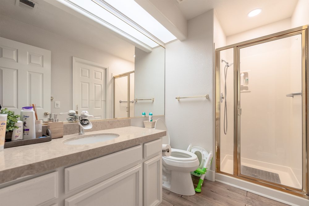 The original bathroom with a cultured marble counter and a brass-framed shower