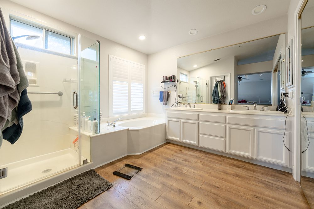The original primary bathroom with a corner tub and white cabinets
