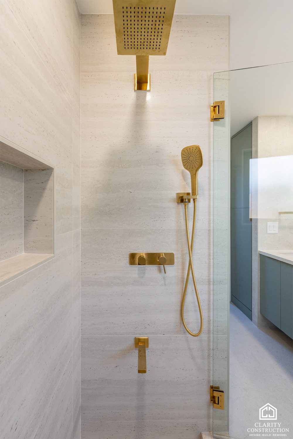 Brass shower fixtures and a recessed niche behind frameless glass