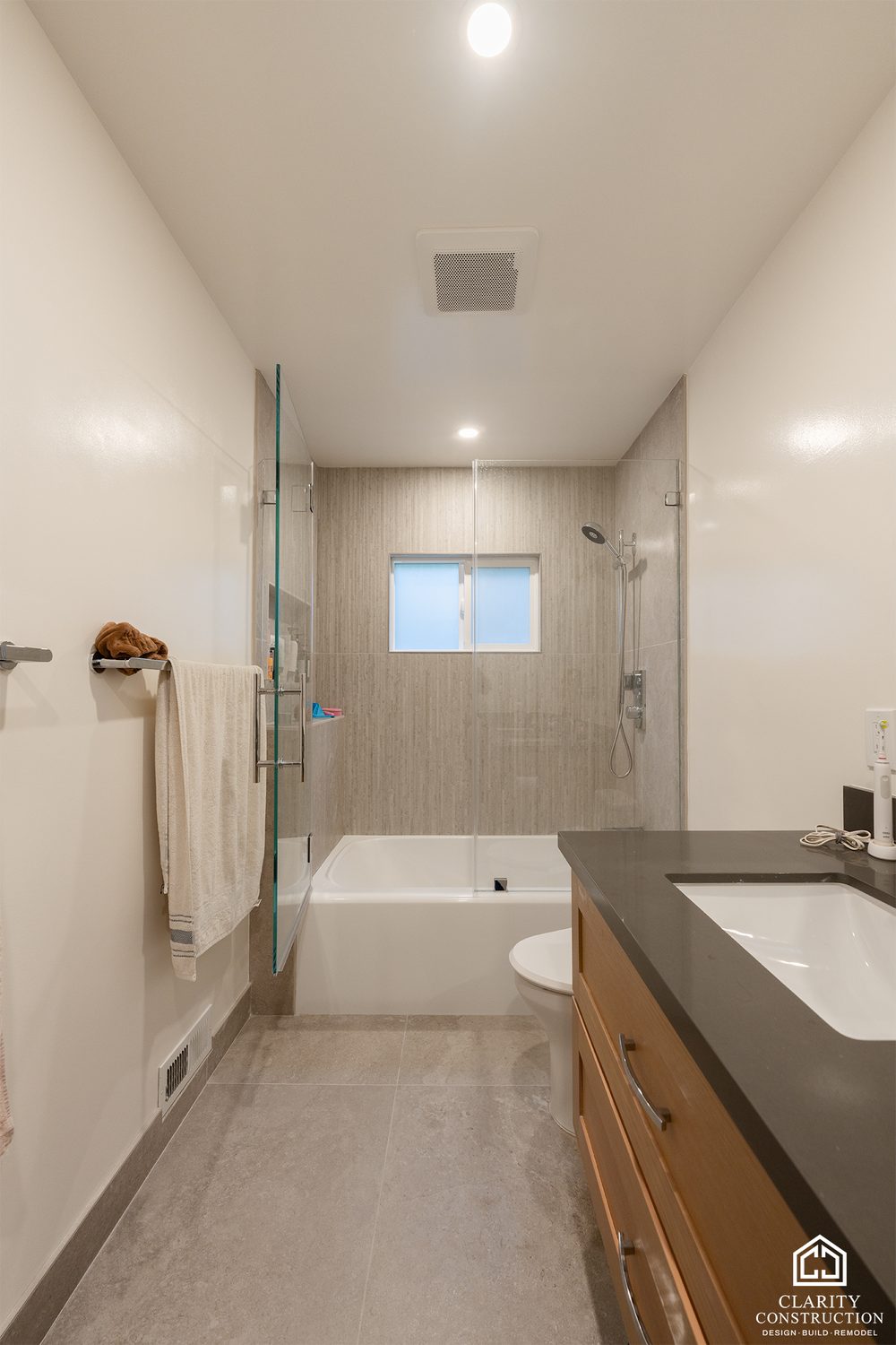 Oak vanity and tub with a glass screen in the first bathroom