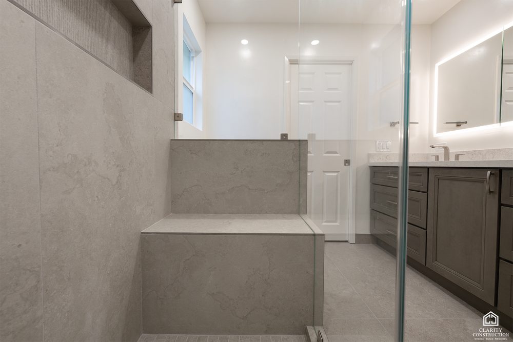 Tiled shower bench behind a half wall of glass