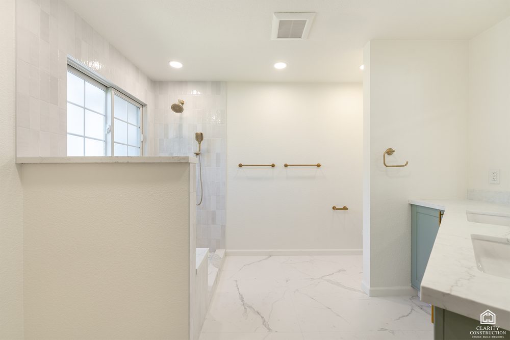 Walk-in shower with a bench under the window and a marble-look floor