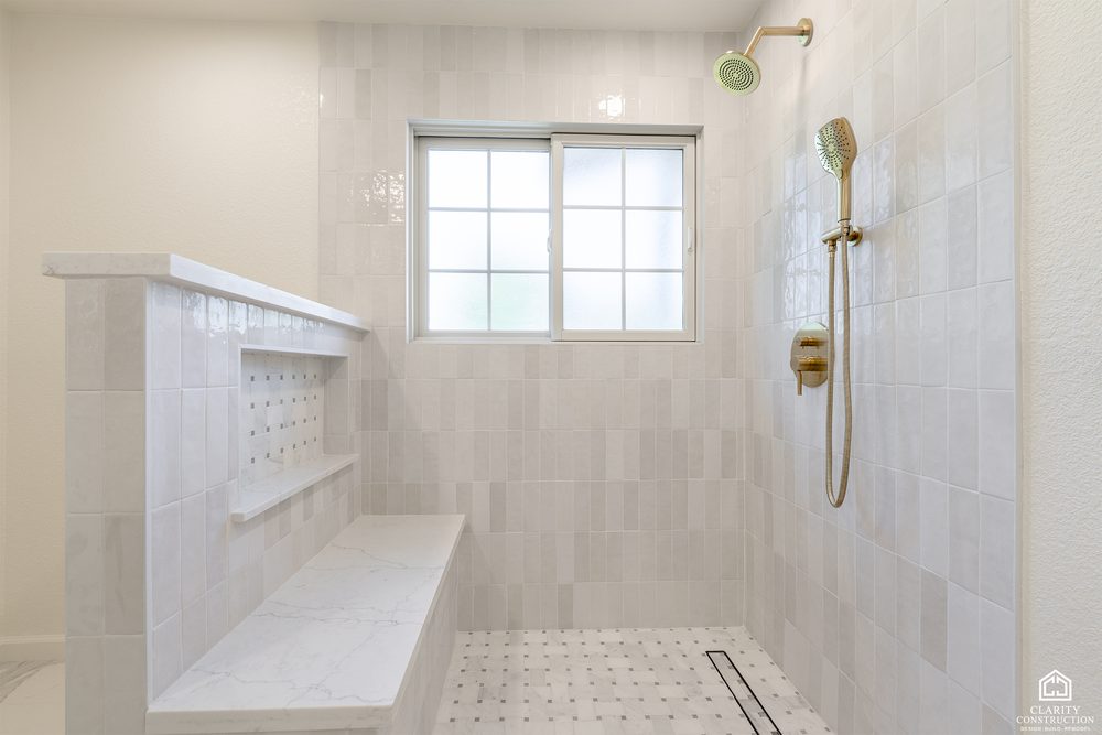 Shower wall with a brass rain head, hand shower and a window