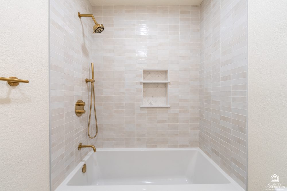Tub and shower with handmade-look tile, a niche and brass fixtures