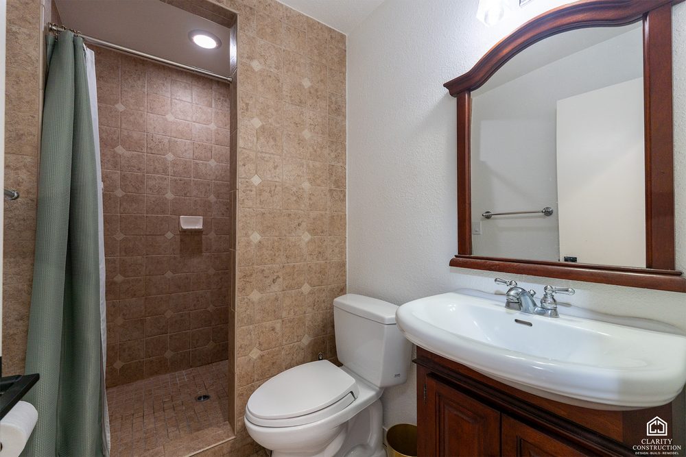 The original guest bathroom with beige tile and a wood-framed mirror