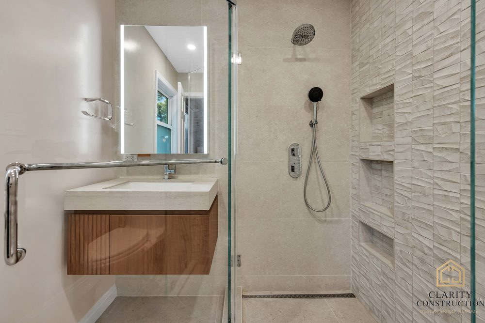 Walk-in shower with chrome fixtures and three tiled niches, seen past the vanity