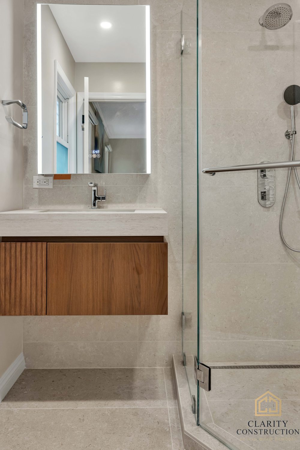 Floating walnut vanity and glass shower enclosure from the bathroom door