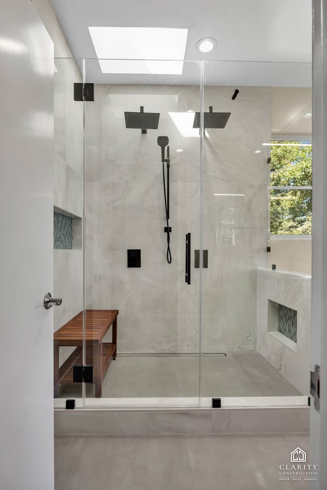 Walk-in shower under a skylight with a rain head and hand shower