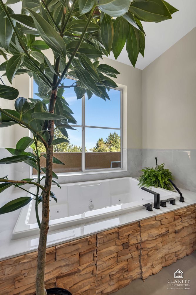 Tub with a stone surround and a plant in the corner