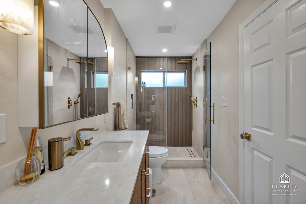 Hall bath: oak vanity with a marble counter, toilet and the walk-in shower beyond