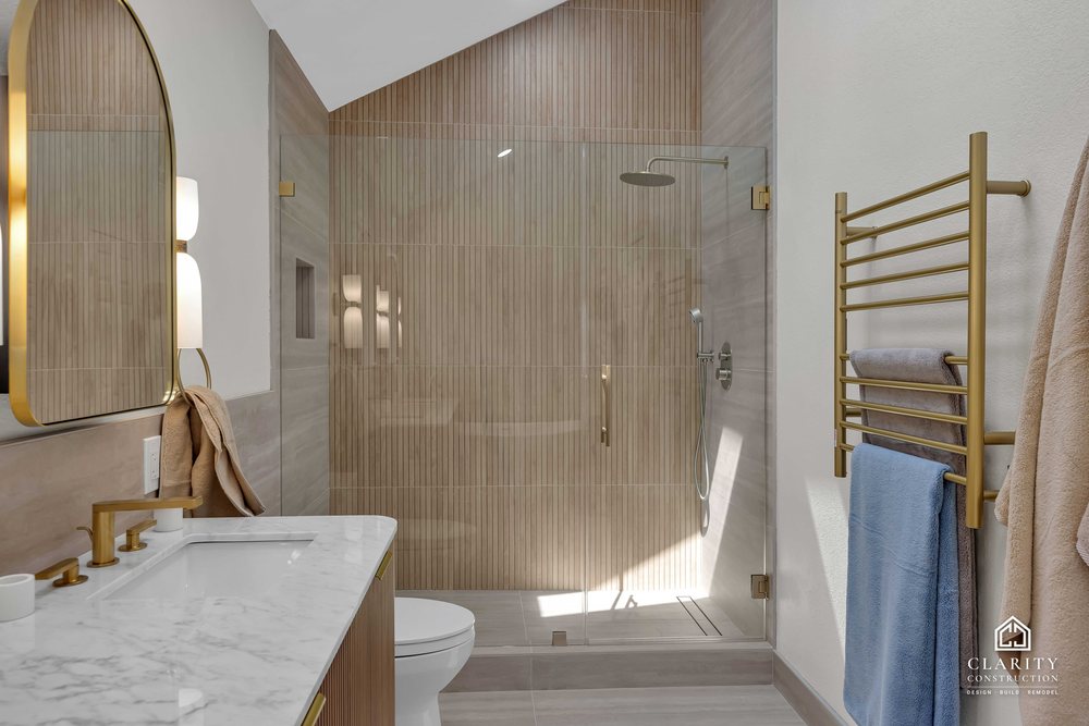 Primary bath: brass towel rail beside the glass walk-in shower