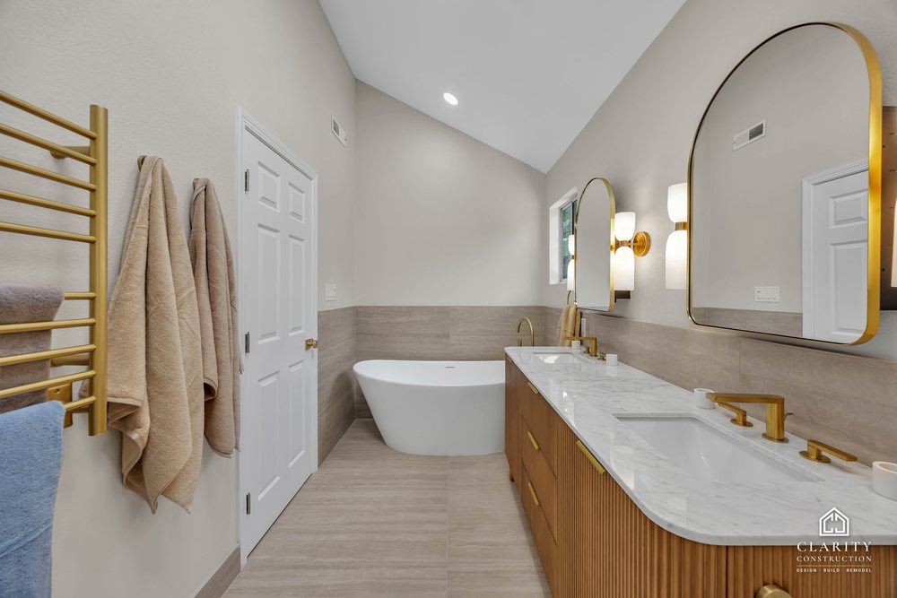 Primary bath: double vanity with arched mirrors and sconces, tub to the left