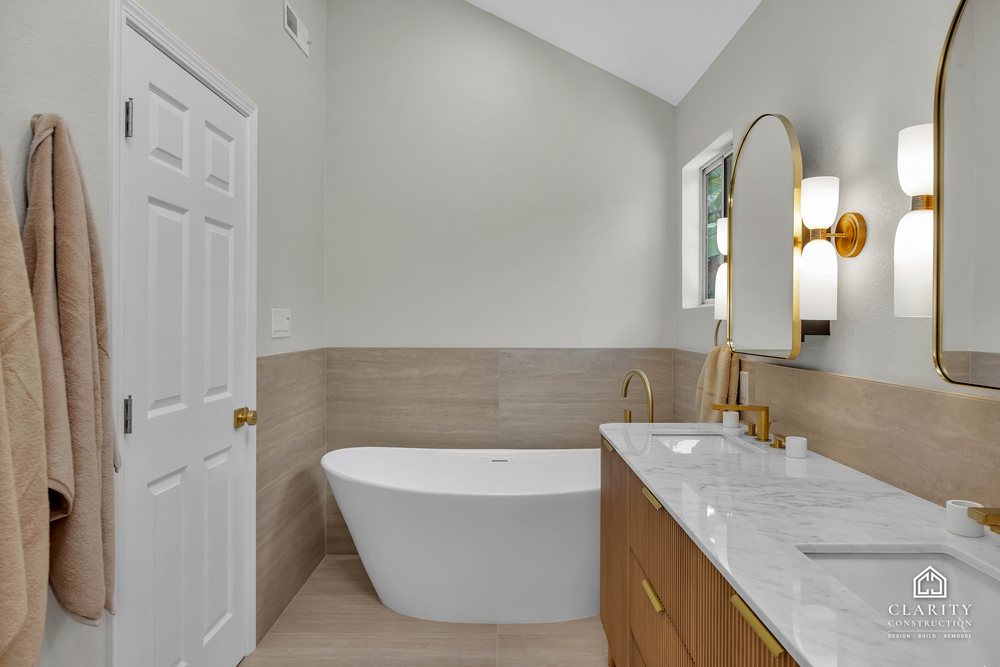 Primary bath: freestanding tub and fluted oak vanity under the vaulted ceiling