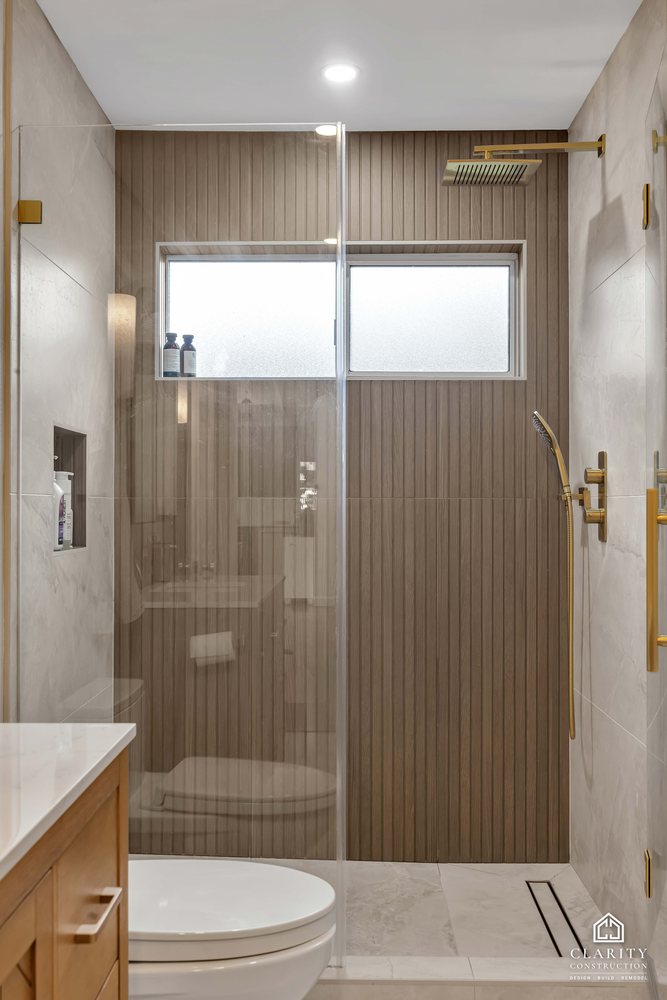 Hall bath: walk-in shower with a window and a brass hand shower