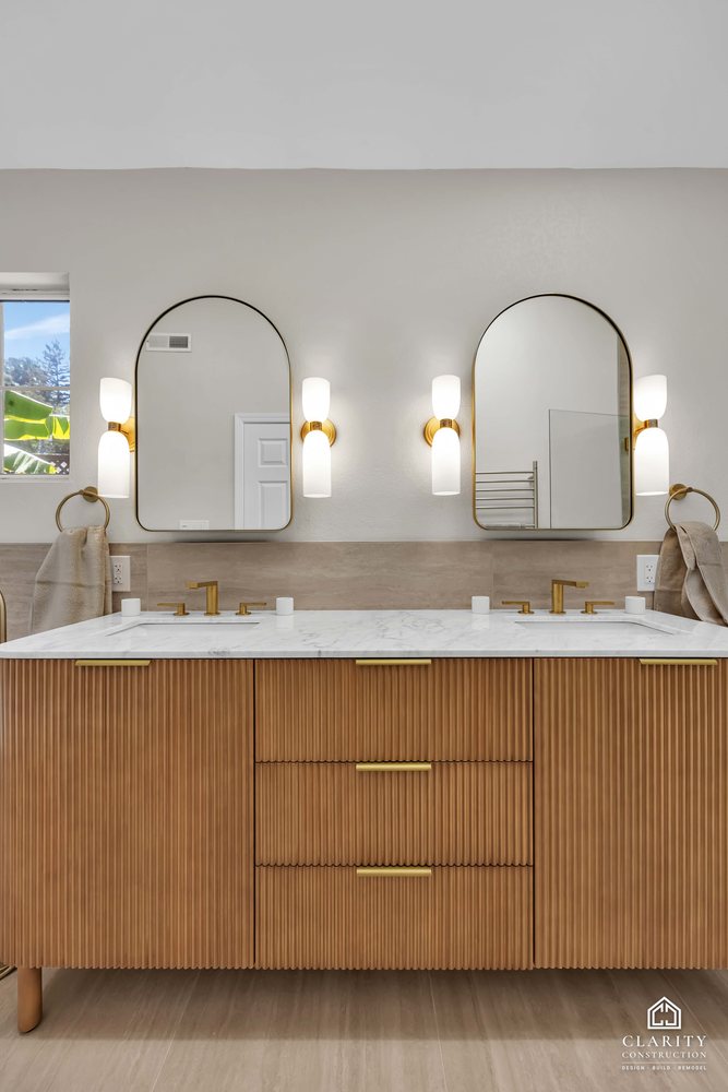 Primary bath: double vanity with arched mirrors and brass sconces
