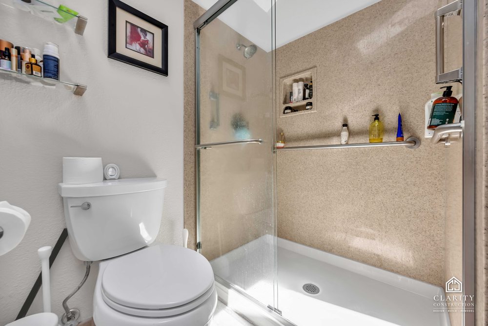 Before: the primary bath with a white vanity, built-in tub and corner shower stall