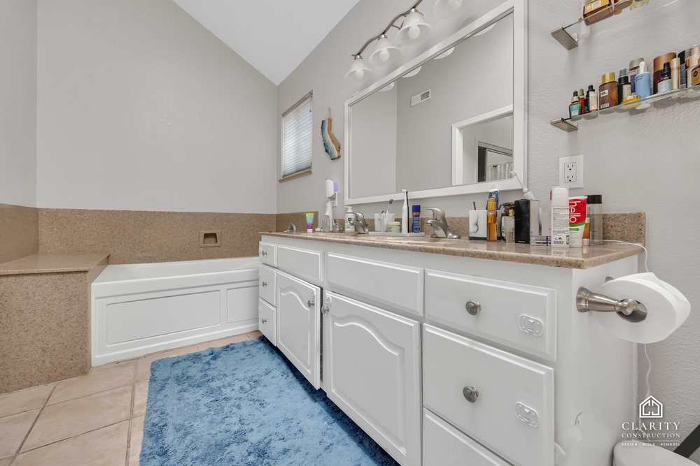 Before: the primary bath with a white vanity, built-in tub and corner shower stall