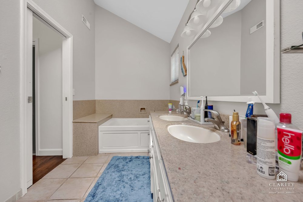 Before: the primary bath with a white vanity, built-in tub and corner shower stall
